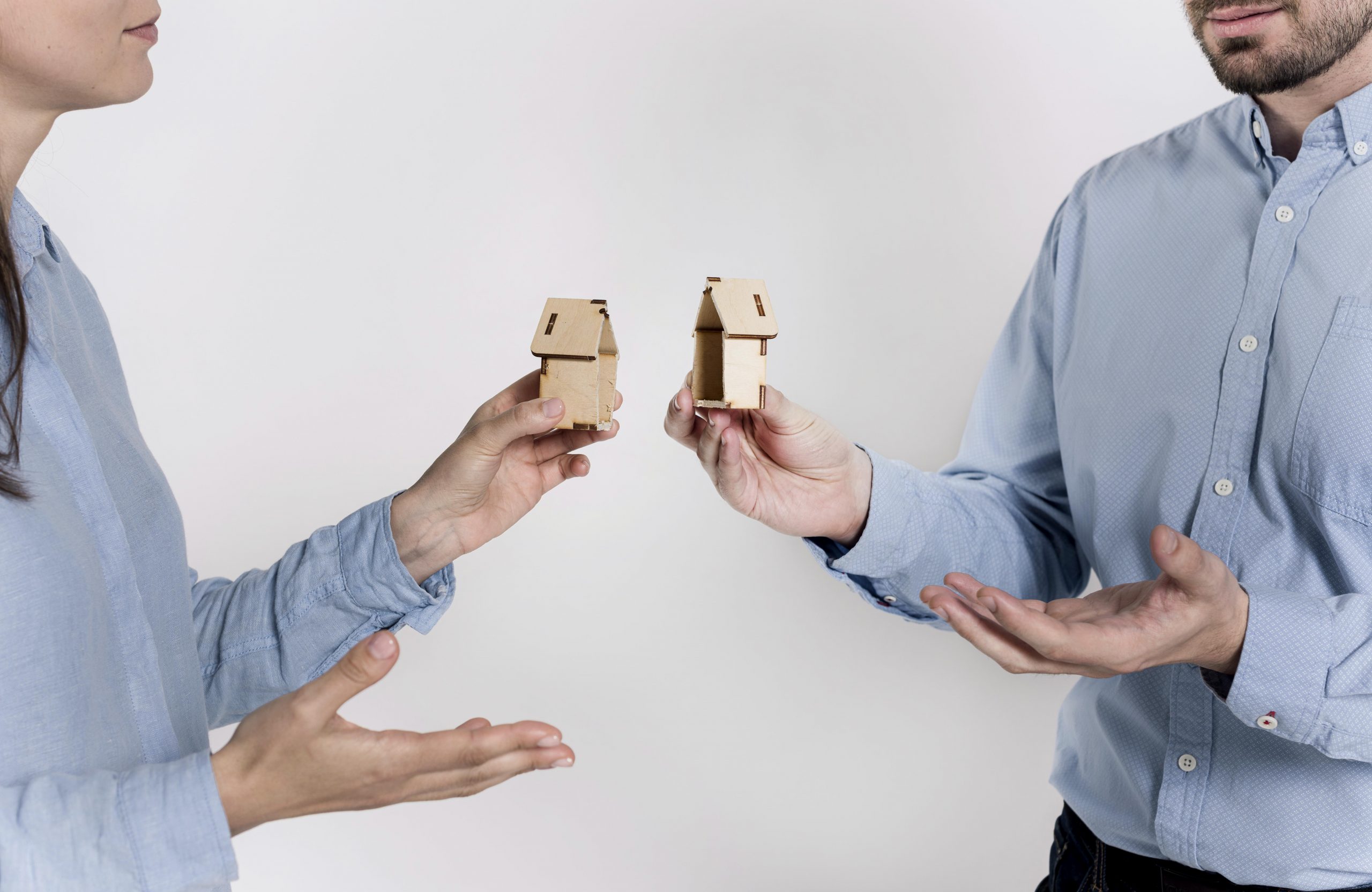 couple holding two halves of a broken house model